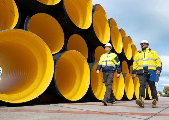 BlackMax corrugated polyethylene drainage pipes laid horizontally at the Iplex Albury distribution yard, highlighting large‑diameter pipe openings and scale.